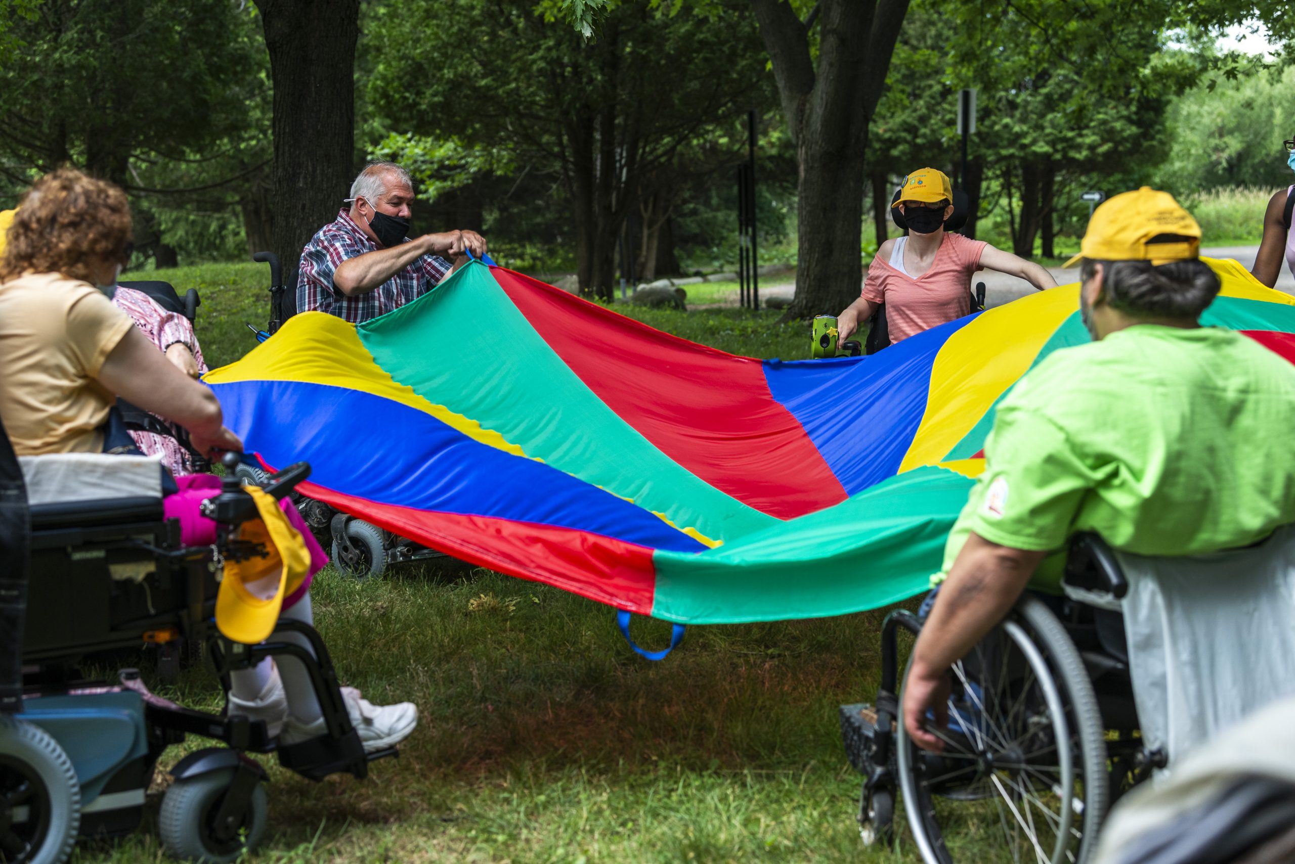 Des adultes en fauteuil roulant s'amusent avec le jeu du parachute.