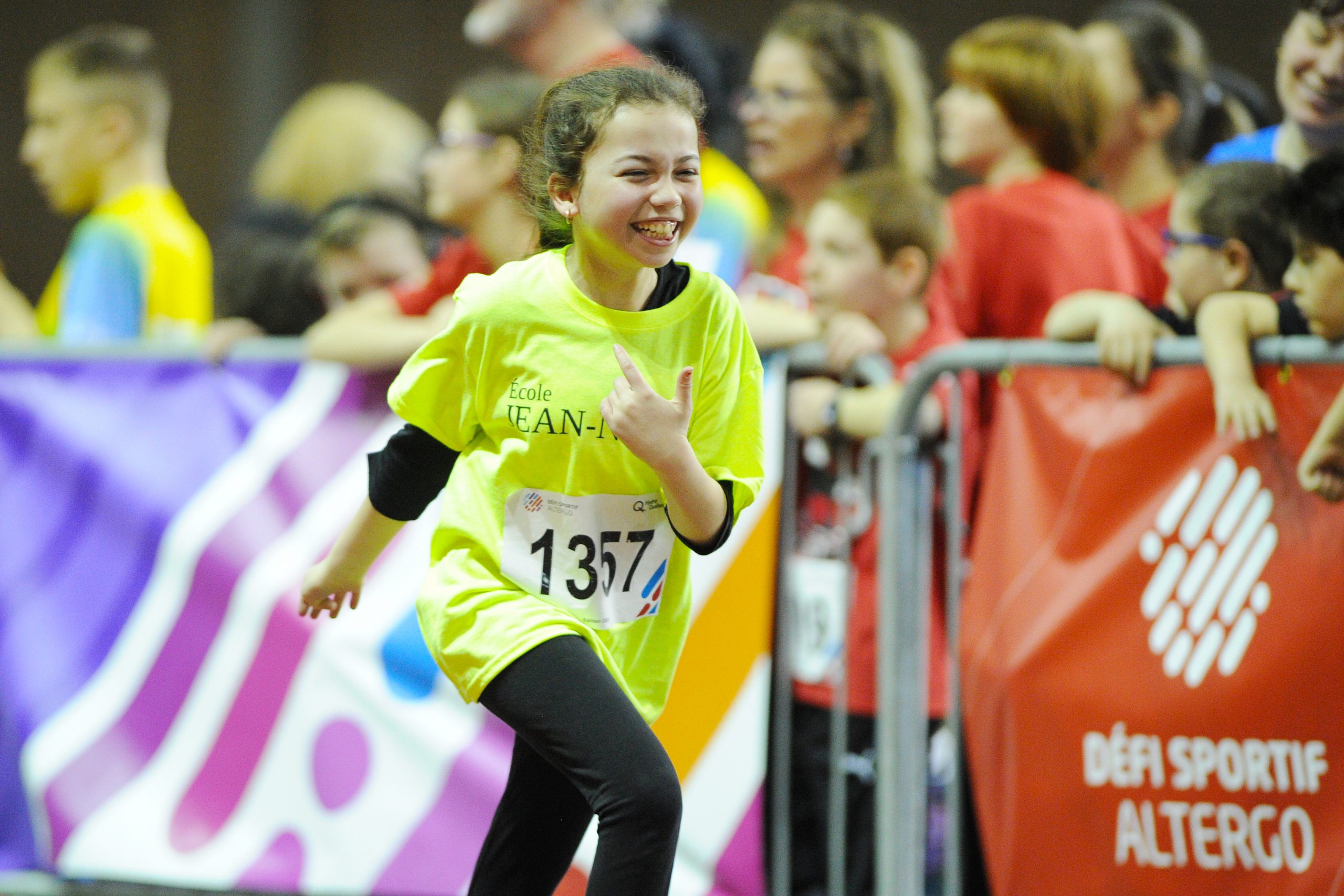 Une jeune fille qui participe au volet scolaire du Défi sportif AlterGo fait une épreuve d'athlétisme avec un grand sourire.