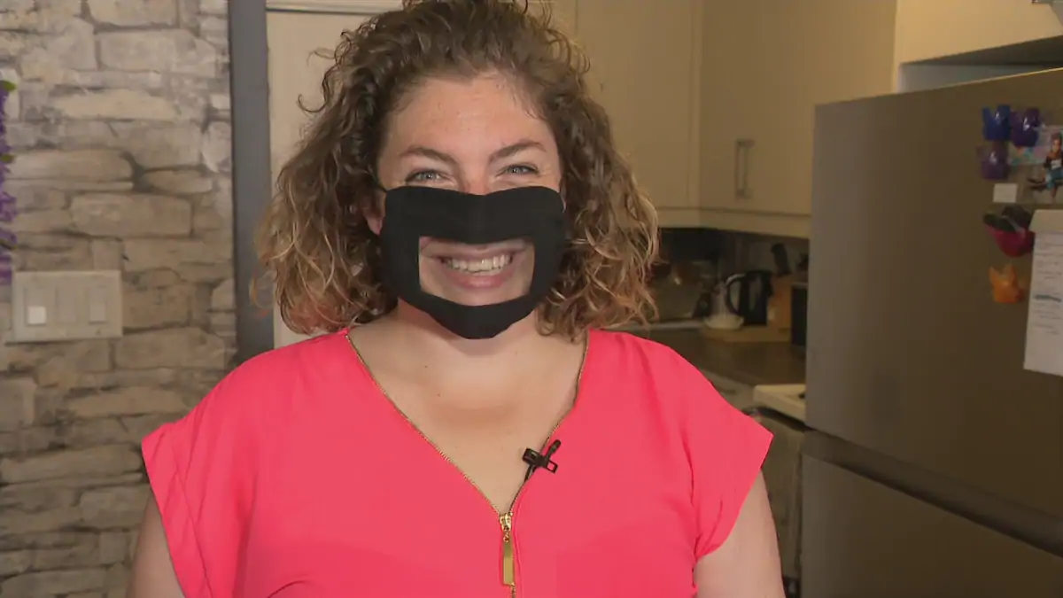 Kim Auclair porte un masque adapté pour les personnes ayant une déficience auditive. Le masque est muni d'une partie transparente en plastique souple.