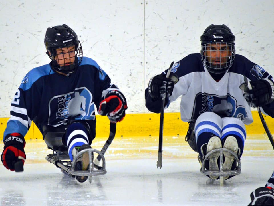 Lors d'un match de parahockey, Guylain Bélanger se retrouve côte à côte avec un autre joueur.