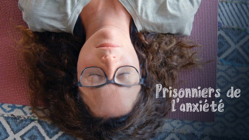 Description de l'image : photo à l'envers de la tête d'une femme ayant des lunettes et les yeux fermés. On peut lire le titre : "Prisonniers de l'anxiété".